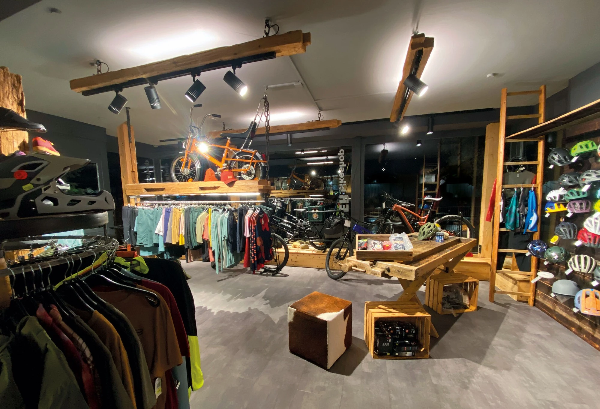 Moderner Fahrradladen mit Holzregalen, Kleidungsst&auml;ndern und ausgestellten Fahrr&auml;dern.