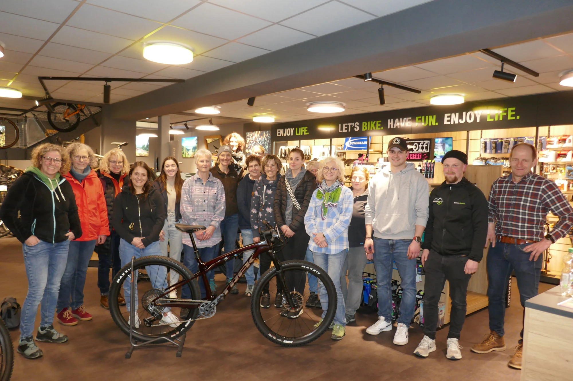 Gruppe von Menschen posiert zusammen mit einem Fahrrad in einem Fahrradgesch&auml;ft.