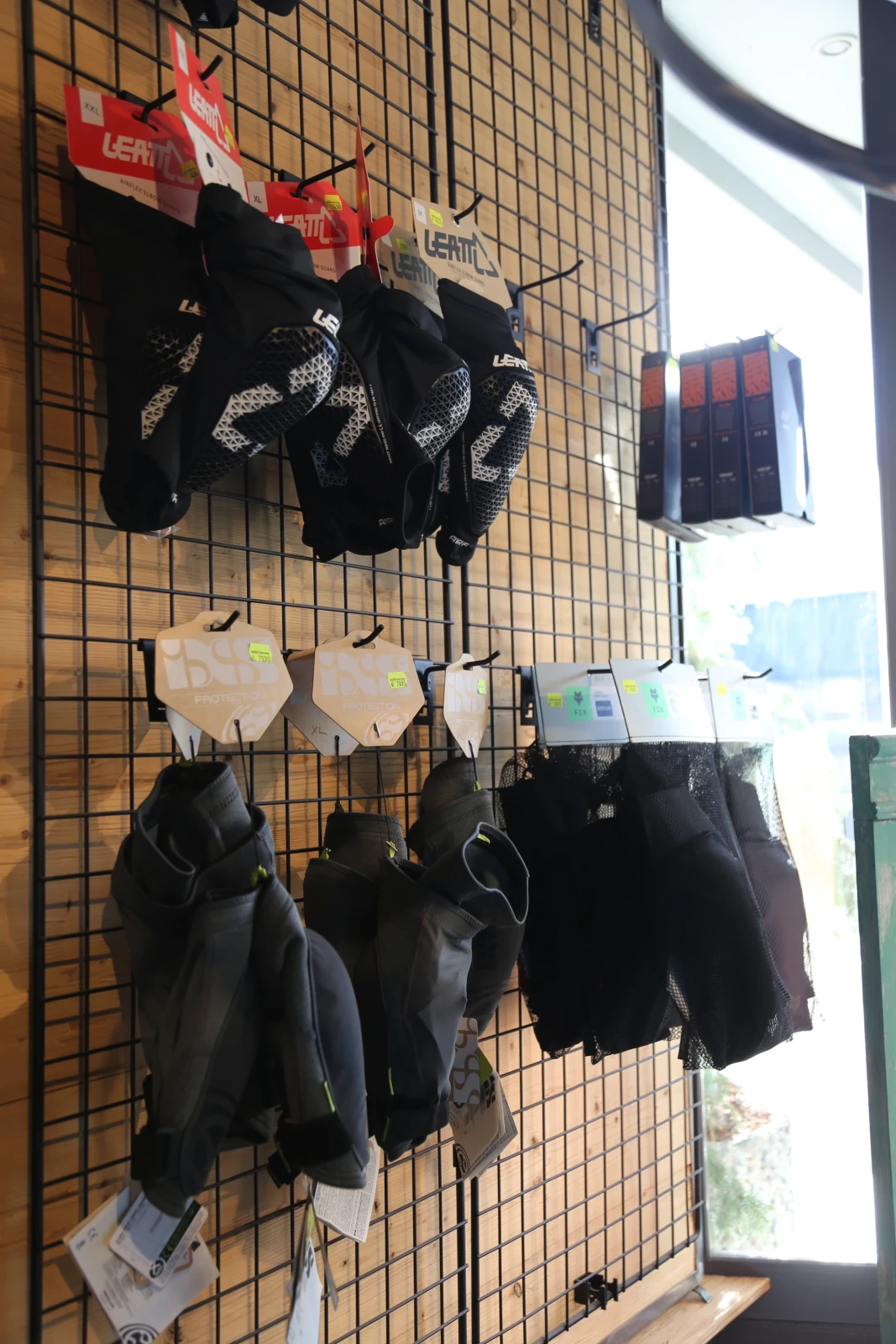 Fahrradhandschuhe und Zubeh&ouml;r in schwarzen und hellen Farben h&auml;ngen an einem Gitterdisplay im Laden.