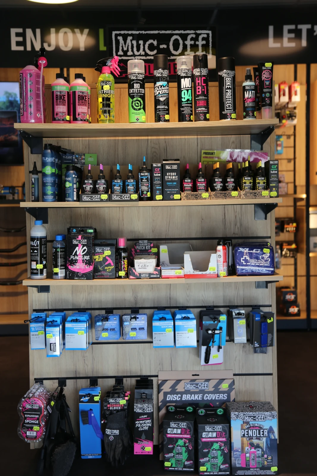 Muc-Off Produktregal mit Reinigungsmitteln, Sprays und Zubeh&ouml;r f&uuml;r Fahrradpflege.