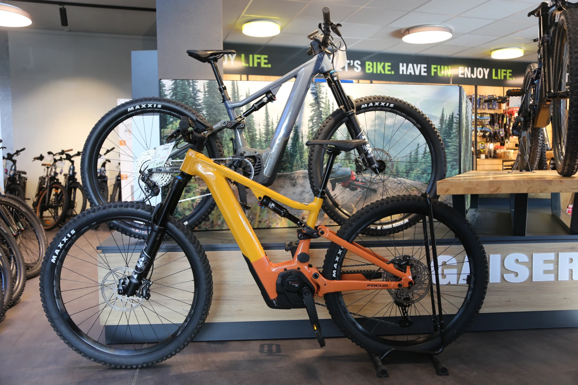 Zwei Mountainbikes in einem Fahrradgesch&auml;ft ausgestellt, eines in Grau-Blau und eines in Orange-Gelb.