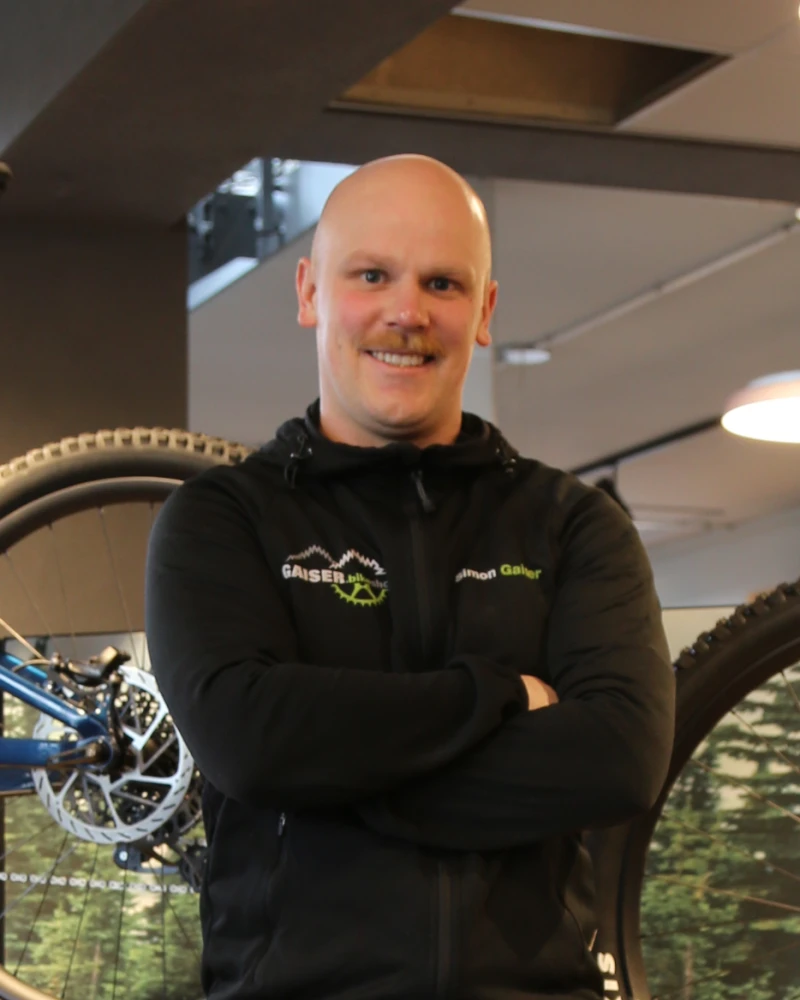 Ein Mann steht l&auml;chelnd in einem Fahrradladen vor ausgestellten Fahrr&auml;dern.