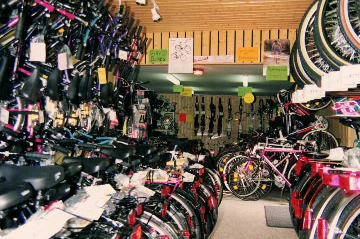 Fahrradwerkstatt mit bunten Fahrr&auml;dern und Zubeh&ouml;r an Wandregalen.