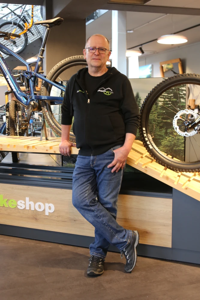J&ouml;rg Gaiser in schwarzem Hoodie vor einem Fahrrad in der Bikeshop-Werkstatt.